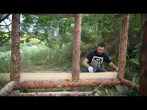 A man builds a wooden house in nature Cooking over a