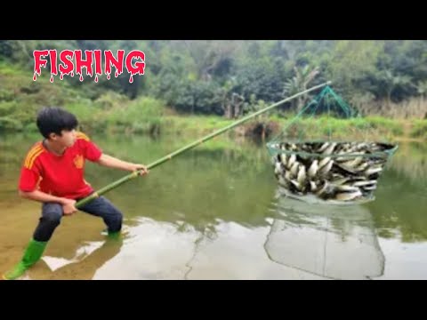 The boy Lam used a green net to catch fish in a big stream