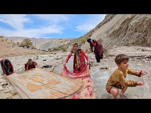 Washing blankets in the raging river by a nomadic family